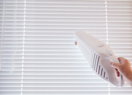 Handheld vacuum cleaning window blinds.