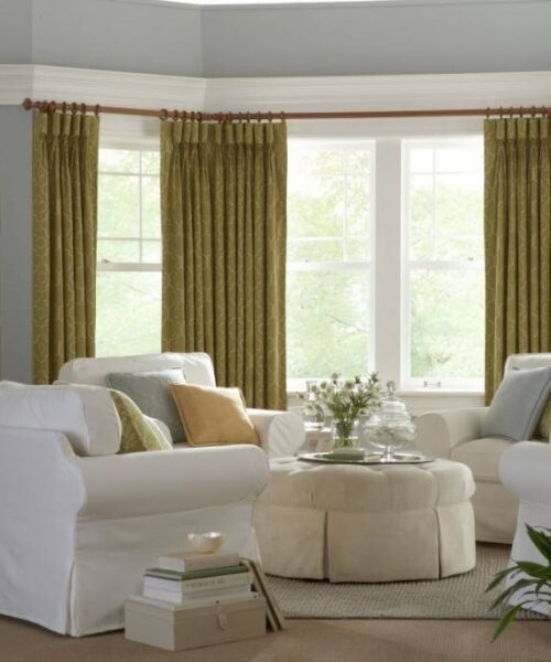 Cozy living room with green curtains and plants.